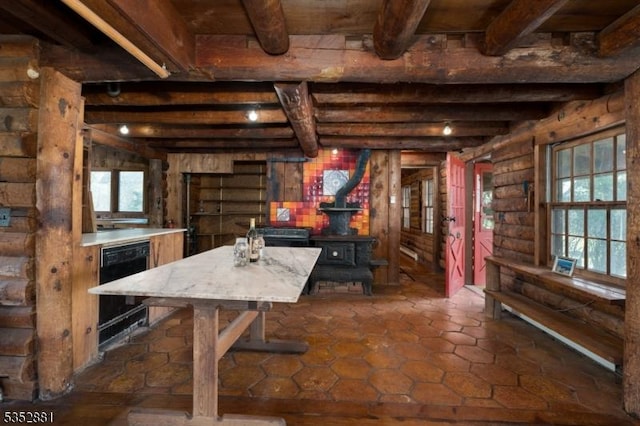 dining room with a wood stove, log walls, and beam ceiling
