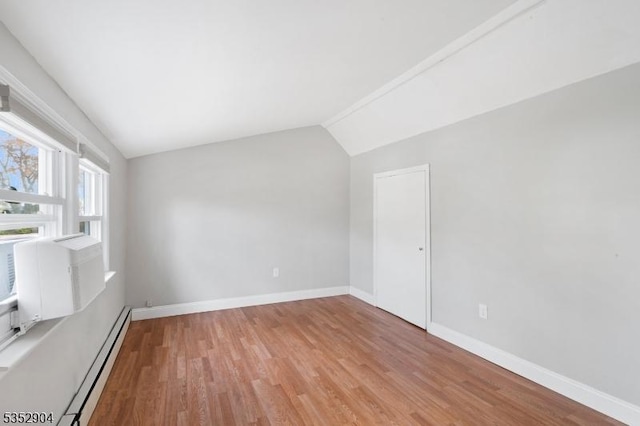 interior space with baseboards, vaulted ceiling, baseboard heating, and light wood finished floors