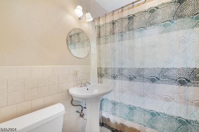 bathroom featuring tile walls, a shower with curtain, and toilet