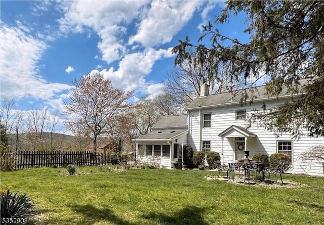 back of property featuring a yard, a chimney, and fence