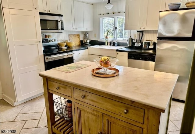 kitchen with a sink, appliances with stainless steel finishes, white cabinets, and a center island