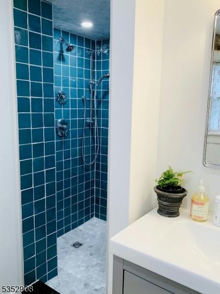 bathroom featuring vanity and tiled shower