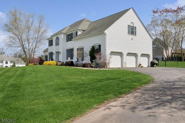 view of property exterior featuring a lawn, driveway, fence, and a garage