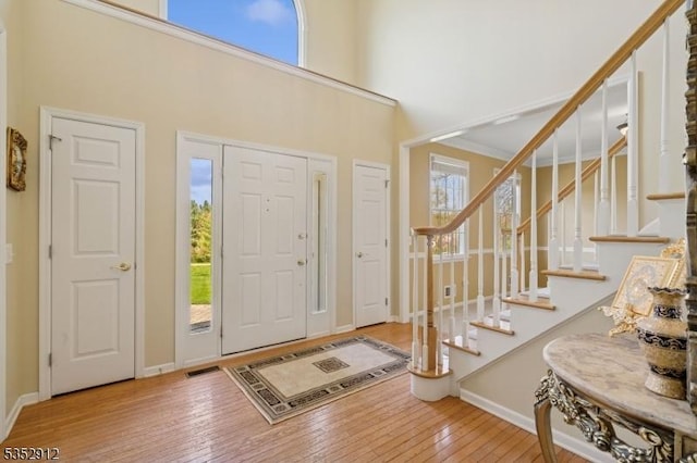 entrance foyer with wood-type flooring, baseboards, a high ceiling, and stairs