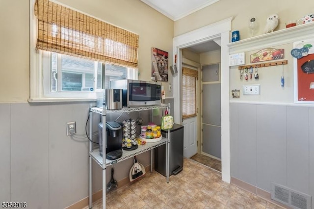 kitchen with visible vents, a decorative wall, and stainless steel microwave