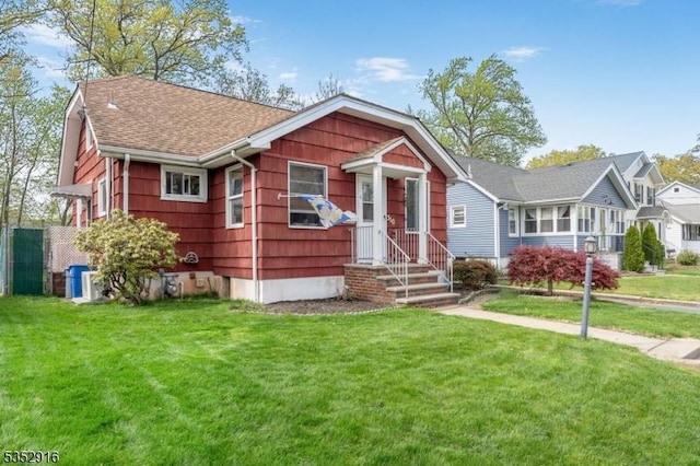 view of front of home with a front yard and a shingled roof