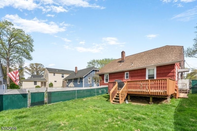 rear view of property with a lawn, a deck, a fenced backyard, and a chimney