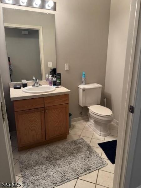 half bath featuring vanity, tile patterned flooring, and toilet