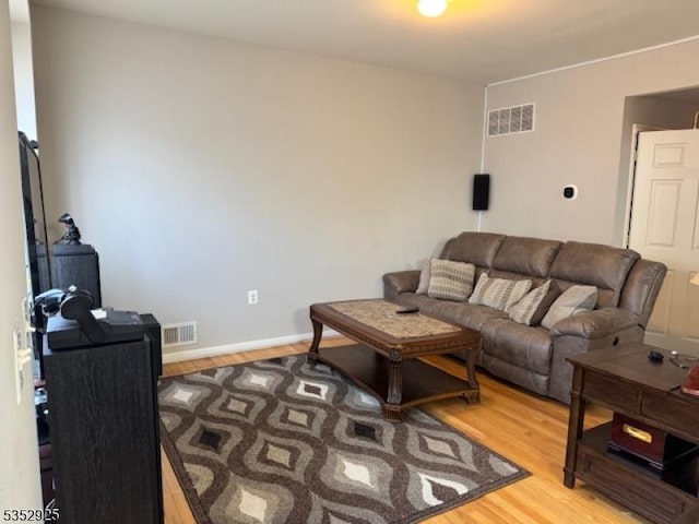 living room with baseboards, light wood-type flooring, and visible vents