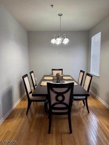 dining space with baseboards, a notable chandelier, and light wood-style flooring