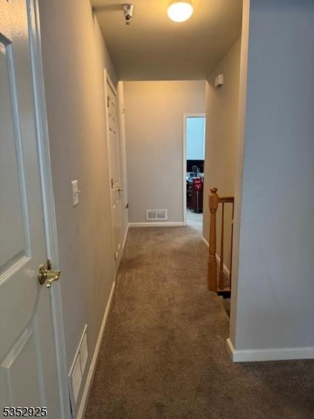 hall with baseboards, visible vents, and carpet