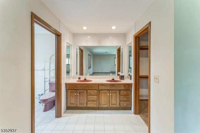 bathroom with double vanity, toilet, tile patterned flooring, and a sink