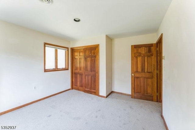 unfurnished bedroom featuring baseboards, a closet, and light colored carpet