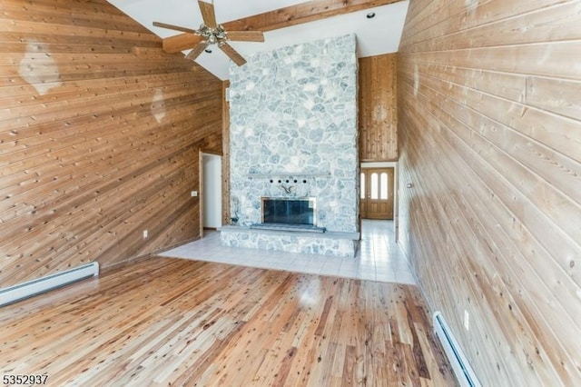 unfurnished living room featuring ceiling fan, wood walls, wood finished floors, and a fireplace