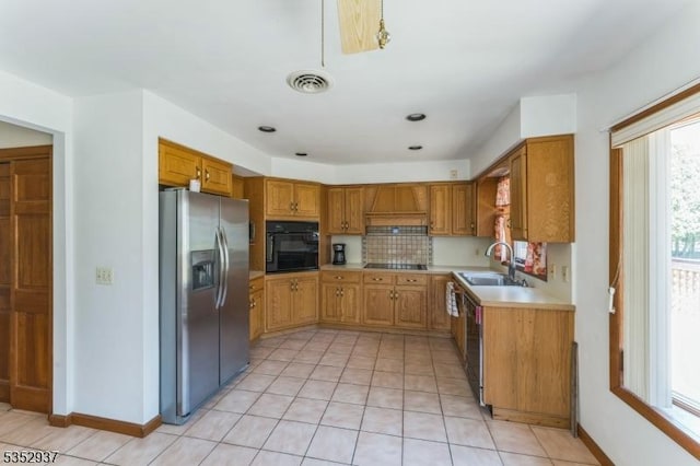 kitchen featuring light tile patterned floors, light countertops, black appliances, a sink, and visible vents