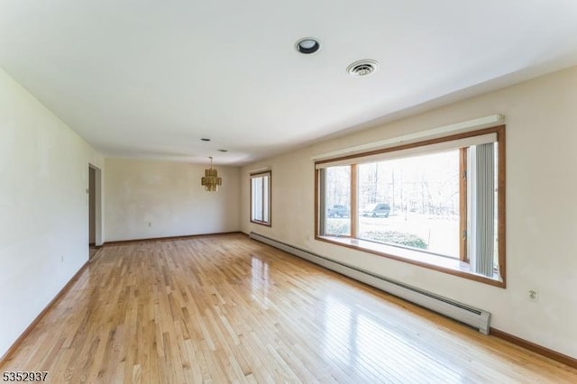 unfurnished room featuring an inviting chandelier, light wood-style floors, baseboard heating, and baseboards
