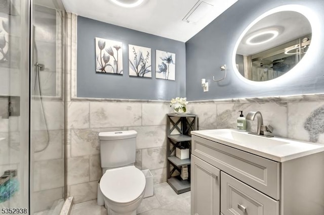 full bath featuring wainscoting, a shower with shower door, vanity, toilet, and tile walls