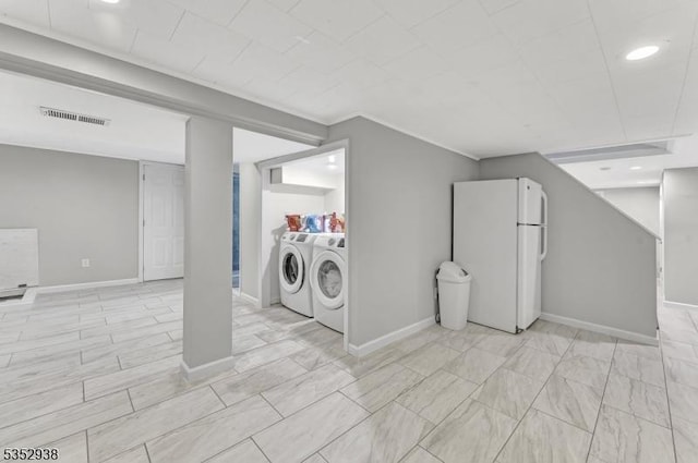 finished below grade area with visible vents, baseboards, freestanding refrigerator, recessed lighting, and washer and clothes dryer
