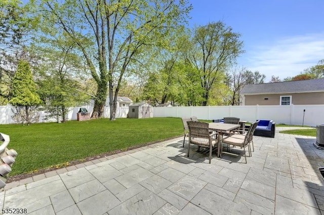 view of patio featuring outdoor dining area, a fenced backyard, a storage shed, and an outdoor structure