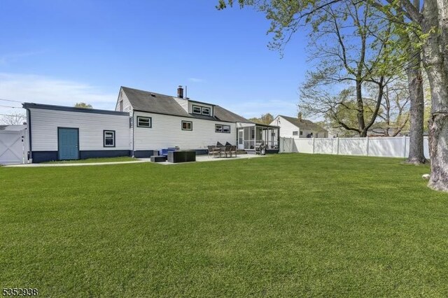 back of house with a lawn, a sunroom, fence private yard, and a patio