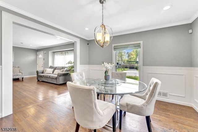 dining area featuring wainscoting, wood finished floors, and a chandelier