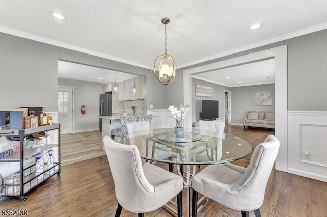 dining area with ornamental molding, wainscoting, recessed lighting, and wood finished floors