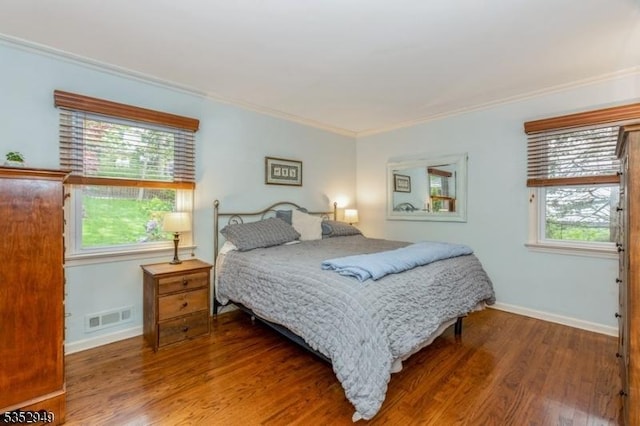 bedroom featuring crown molding, baseboards, visible vents, and wood finished floors