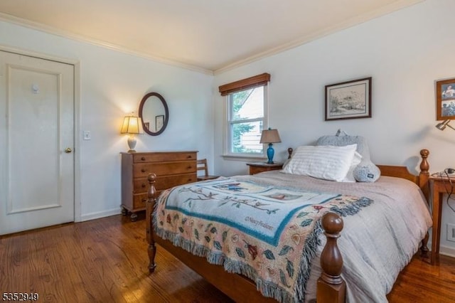 bedroom with baseboards, ornamental molding, and wood finished floors