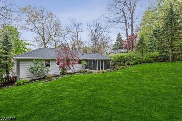 rear view of house with a yard, fence, and a sunroom