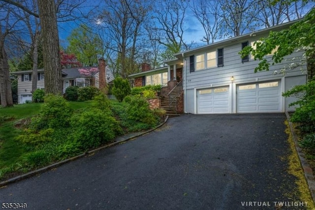 view of side of property featuring stairway, aphalt driveway, and a garage
