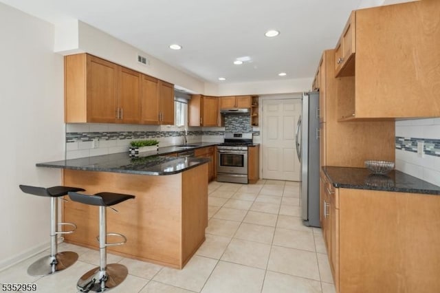 kitchen with decorative backsplash, under cabinet range hood, visible vents, a peninsula, and appliances with stainless steel finishes