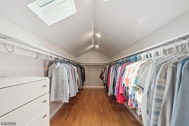 spacious closet featuring lofted ceiling with skylight and wood finished floors