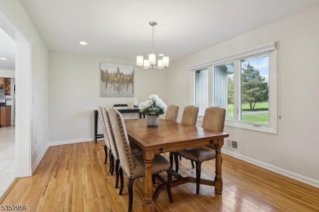 dining space with a notable chandelier, light wood finished floors, visible vents, and baseboards