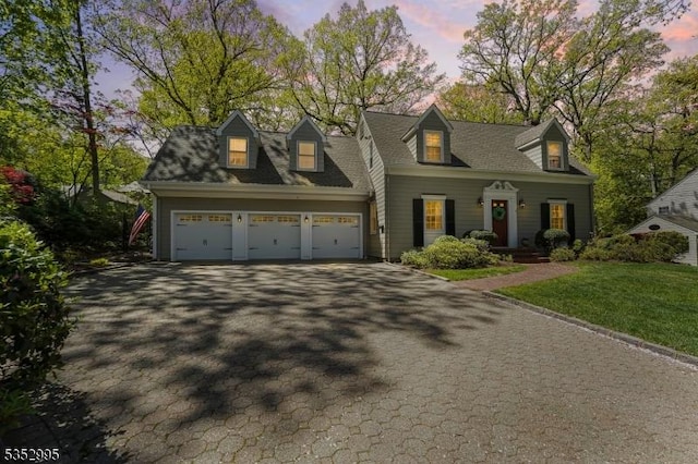 cape cod-style house featuring a porch, an attached garage, driveway, and a yard