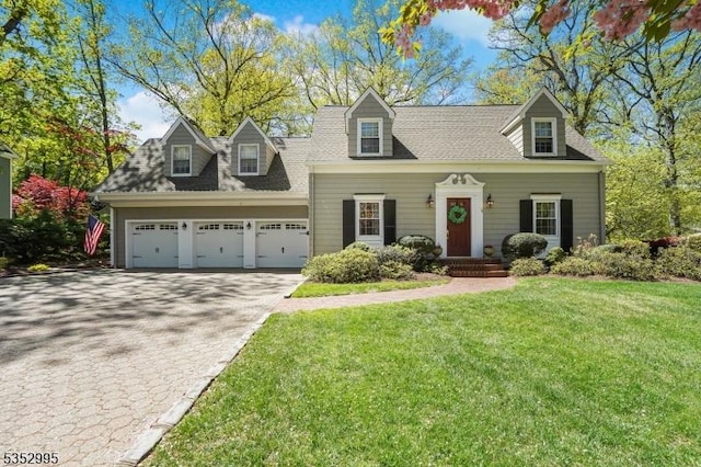 cape cod-style house with decorative driveway, an attached garage, a front yard, and roof with shingles
