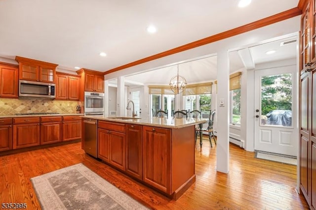 kitchen with a sink, light wood finished floors, baseboard heating, and stainless steel appliances
