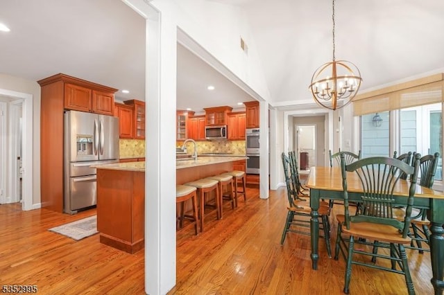 dining area with light wood-type flooring, recessed lighting, and a notable chandelier
