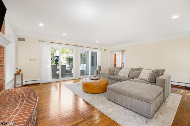 living area featuring visible vents, a fireplace, baseboard heating, wood finished floors, and ornamental molding