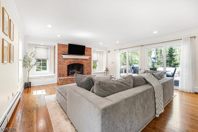 living room featuring crown molding, baseboard heating, and a healthy amount of sunlight