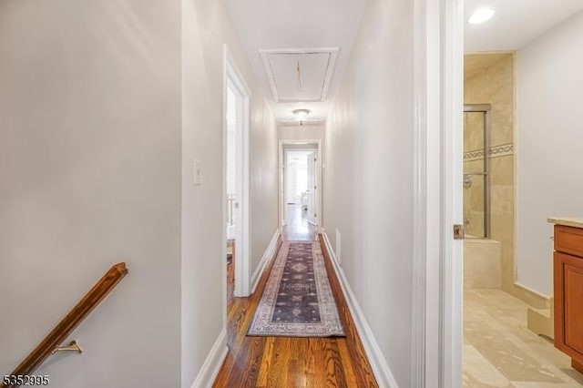 hall featuring attic access, light wood finished floors, and an upstairs landing