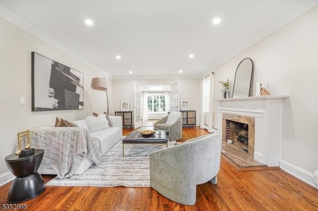 living area featuring crown molding, wood finished floors, baseboards, recessed lighting, and a premium fireplace