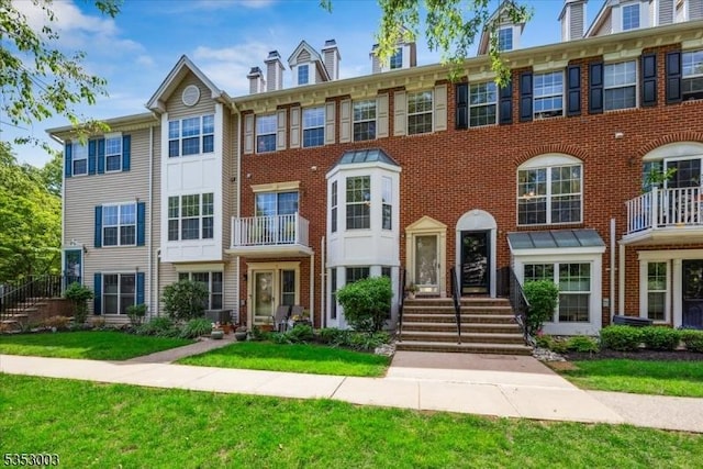 townhome / multi-family property with a front yard and brick siding