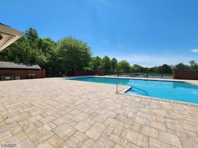 community pool with fence and a patio area