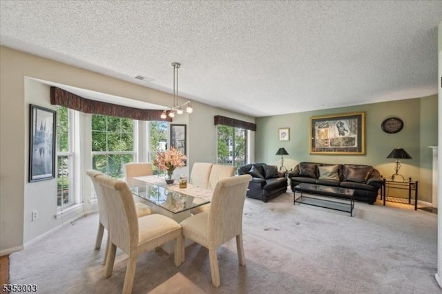 carpeted dining space with a textured ceiling and baseboards