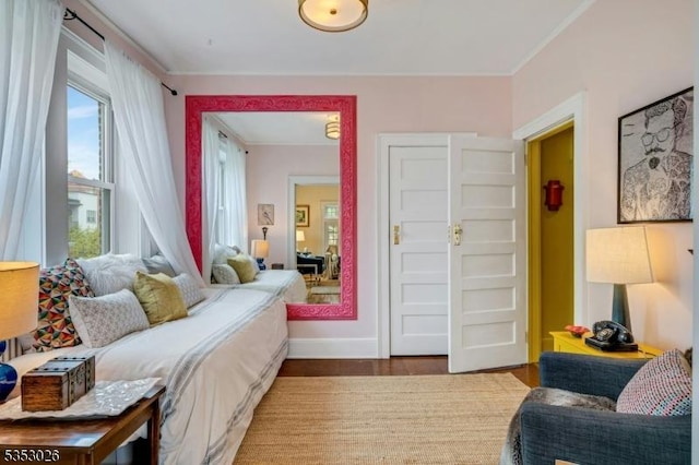bedroom featuring baseboards, wood finished floors, and crown molding