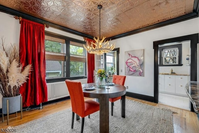 dining area featuring crown molding, baseboards, an ornate ceiling, wood finished floors, and a notable chandelier