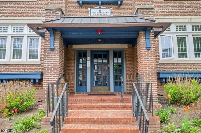 entrance to property featuring metal roof, a standing seam roof, and brick siding