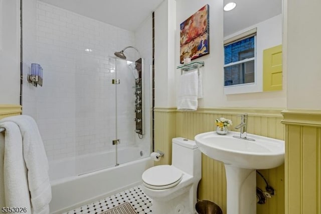 full bathroom with a sink, toilet, shower / bath combination, tile patterned floors, and wainscoting