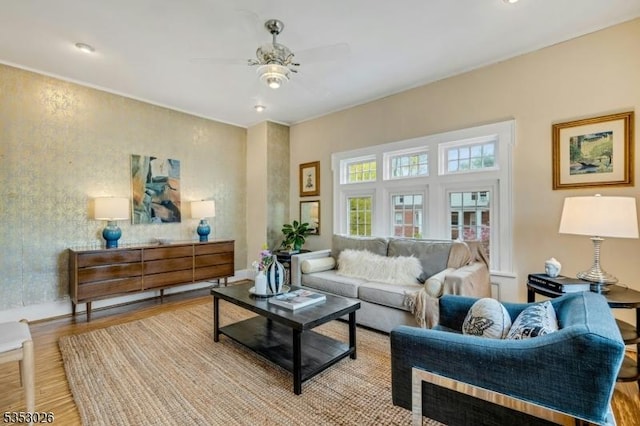 living room with ceiling fan, light wood-style flooring, and baseboards