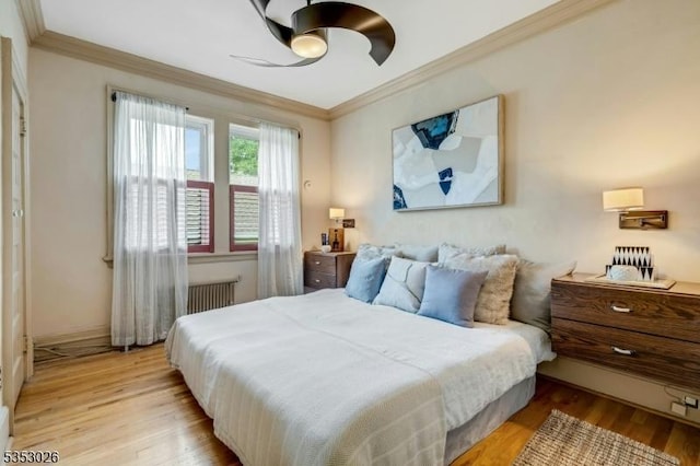 bedroom with light wood finished floors, radiator heating unit, ornamental molding, and a ceiling fan
